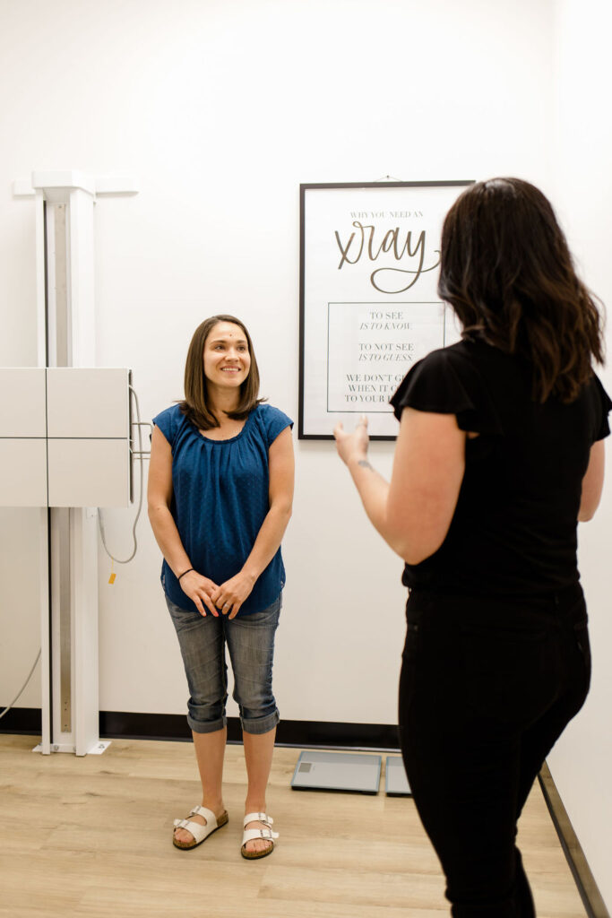 chiropractor explaining to teenager what to expect during chiropractic visit